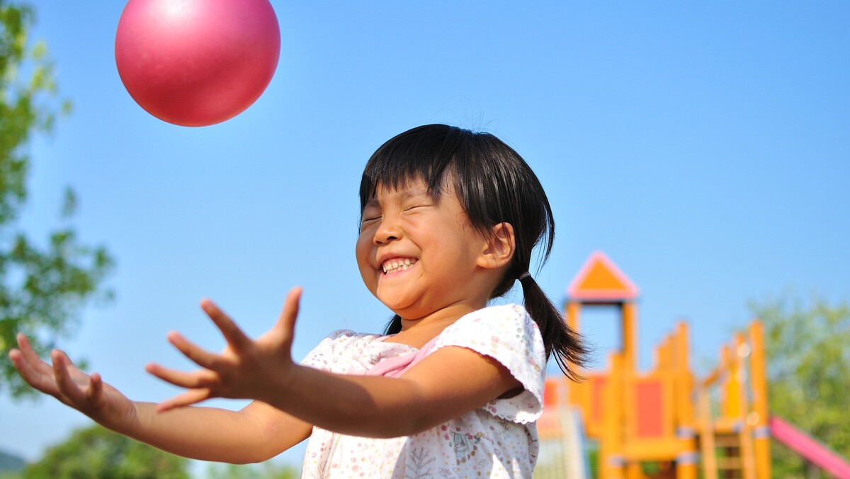 A girl with her hands out and a ball is in the air