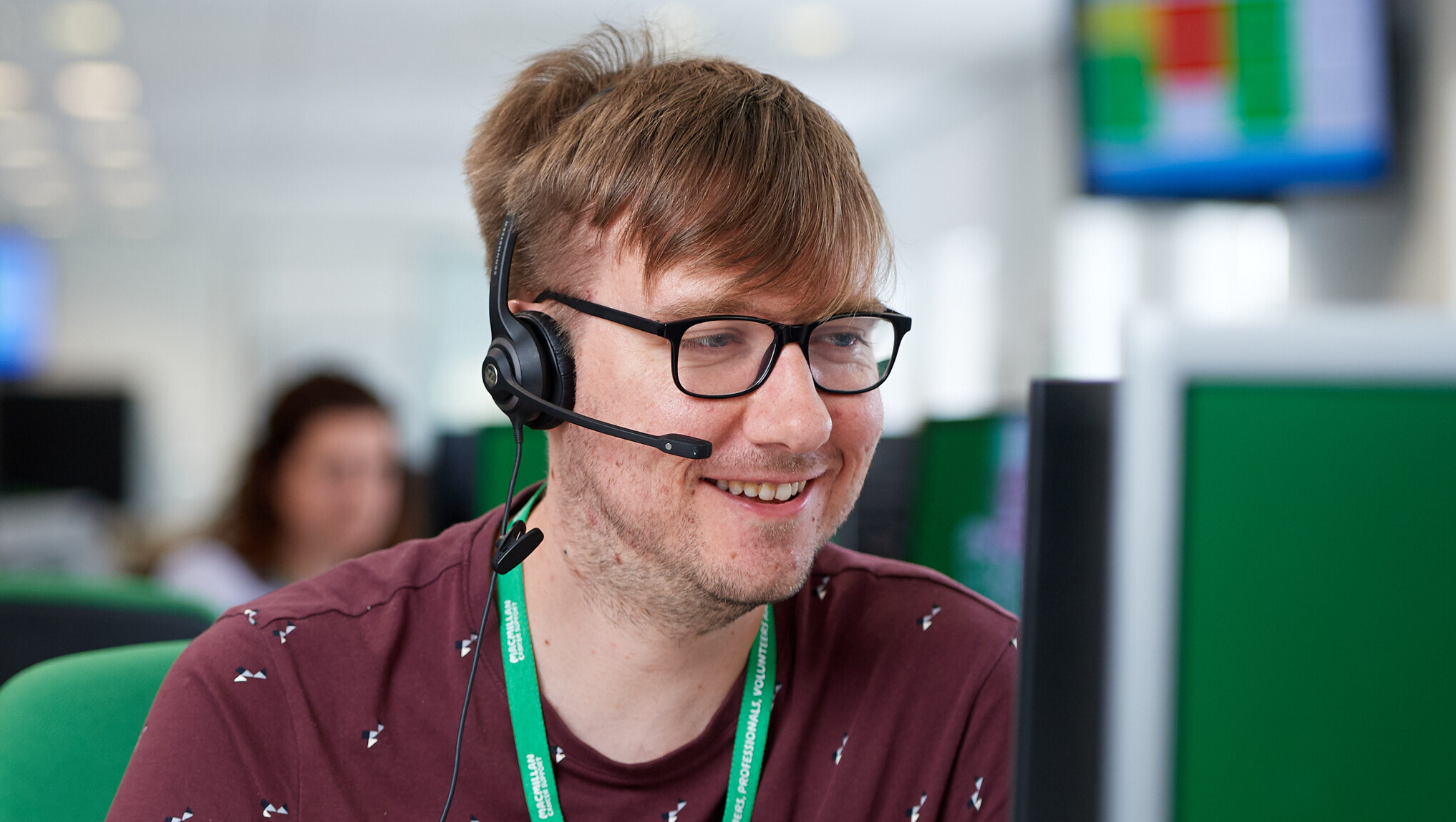 A man smiling while talking into a headset