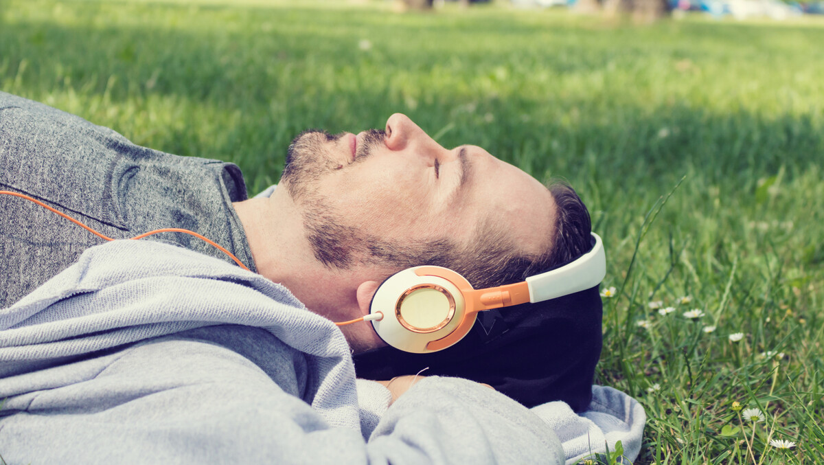 Man lying down in a park listening to music