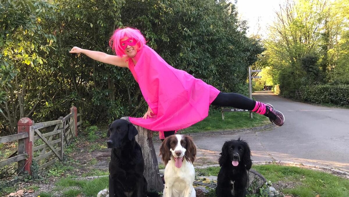 A woman wearing pink fancy dress with three dogs