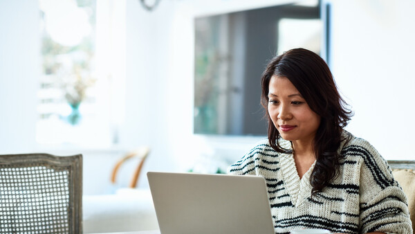 An woman of East Asian heritage is browsing on her laptop.