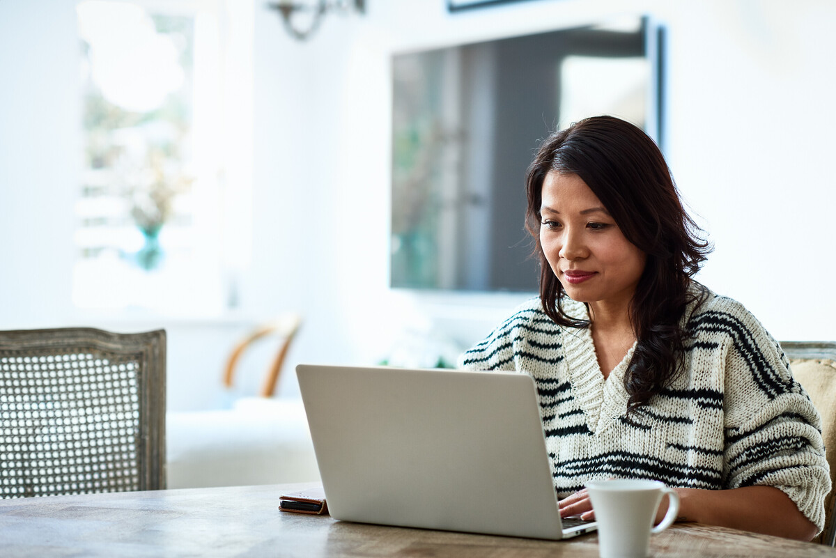 An woman of East Asian heritage is browsing on her laptop.