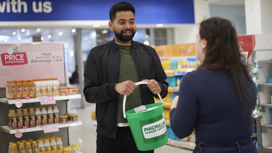 A man holding a Macmillan bucket in a shop