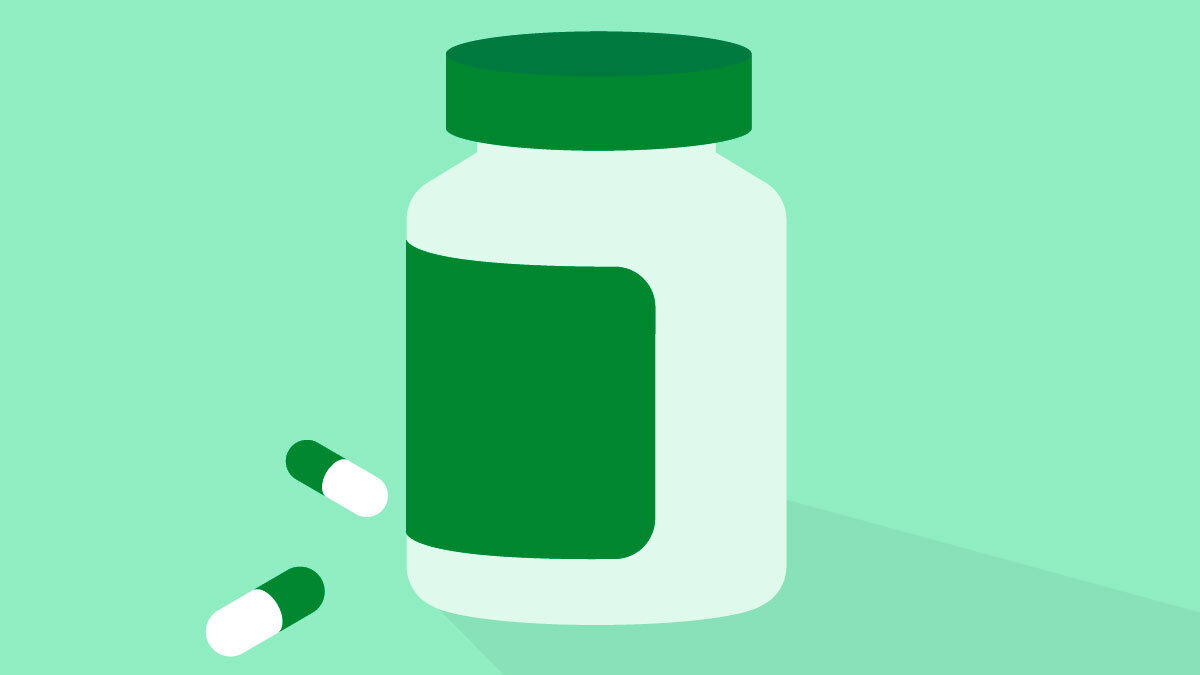A plastic container for pills with two capsules on a light green background.