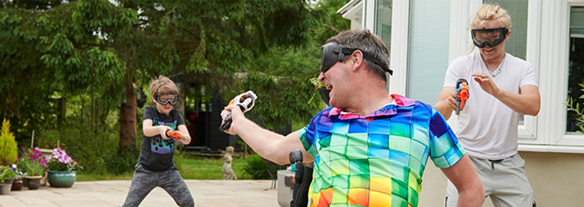 Mark, diagnosed with MS. Mark uses a wheelchair while playing with his family with water guns in the garden.