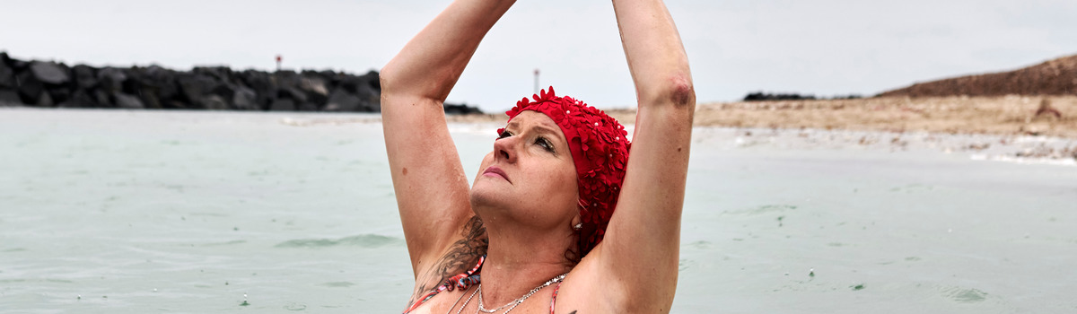 Darlaine, diagnosed with breast cancer. A woman stands in the sea in a swimming costume.