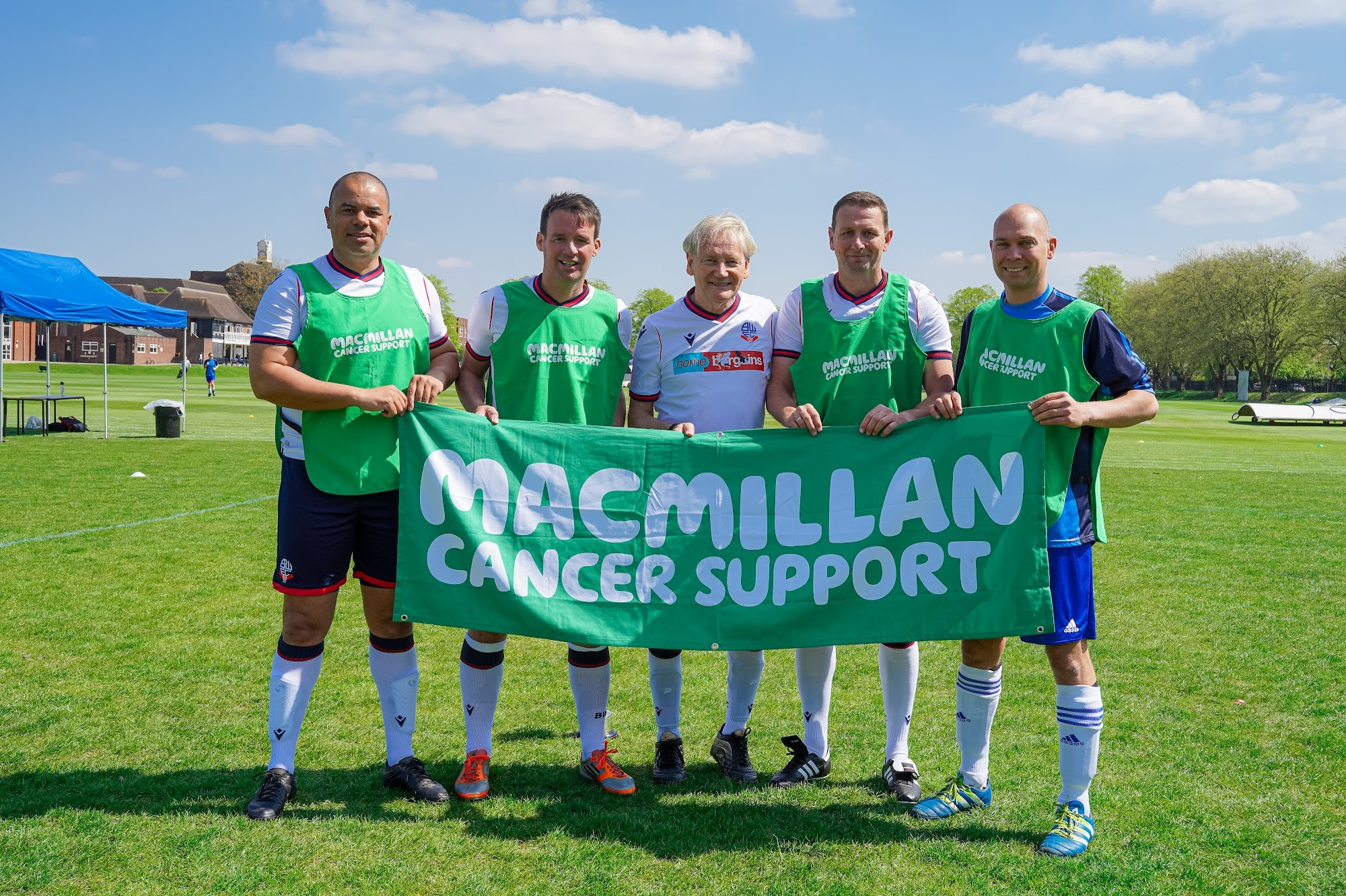 Five footballers holding a Macmillan banner at Manchester Grammar School Match 4 Macmillan.