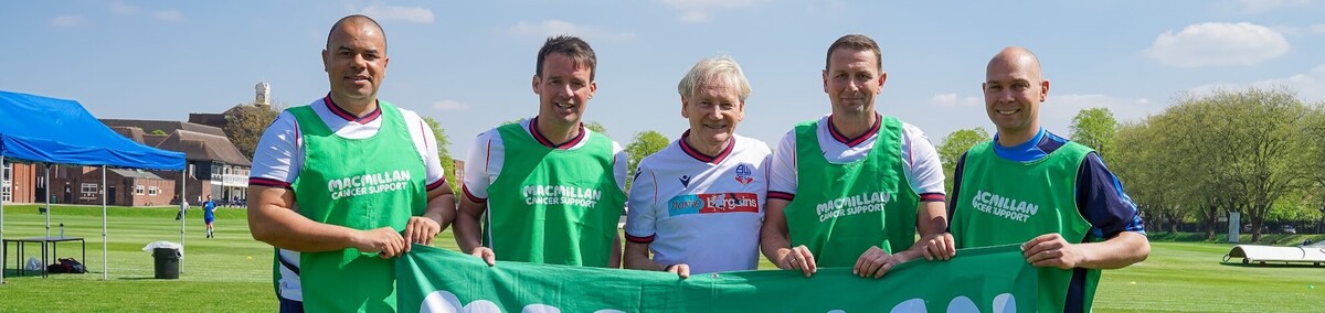 Five footballers holding a Macmillan banner at Manchester Grammar School Match 4 Macmillan.
