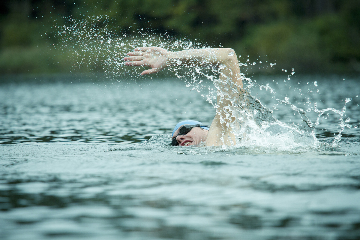 A man swimming wearing a swim cap and goggles does the front crawl in open water