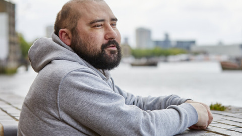 Julian is a man with a beard wearing a grey hoodie.