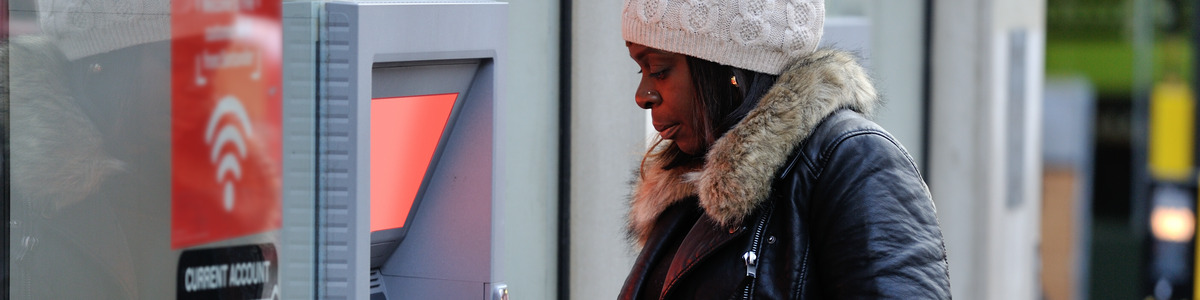 A black woman withdrawing cash (Shola)