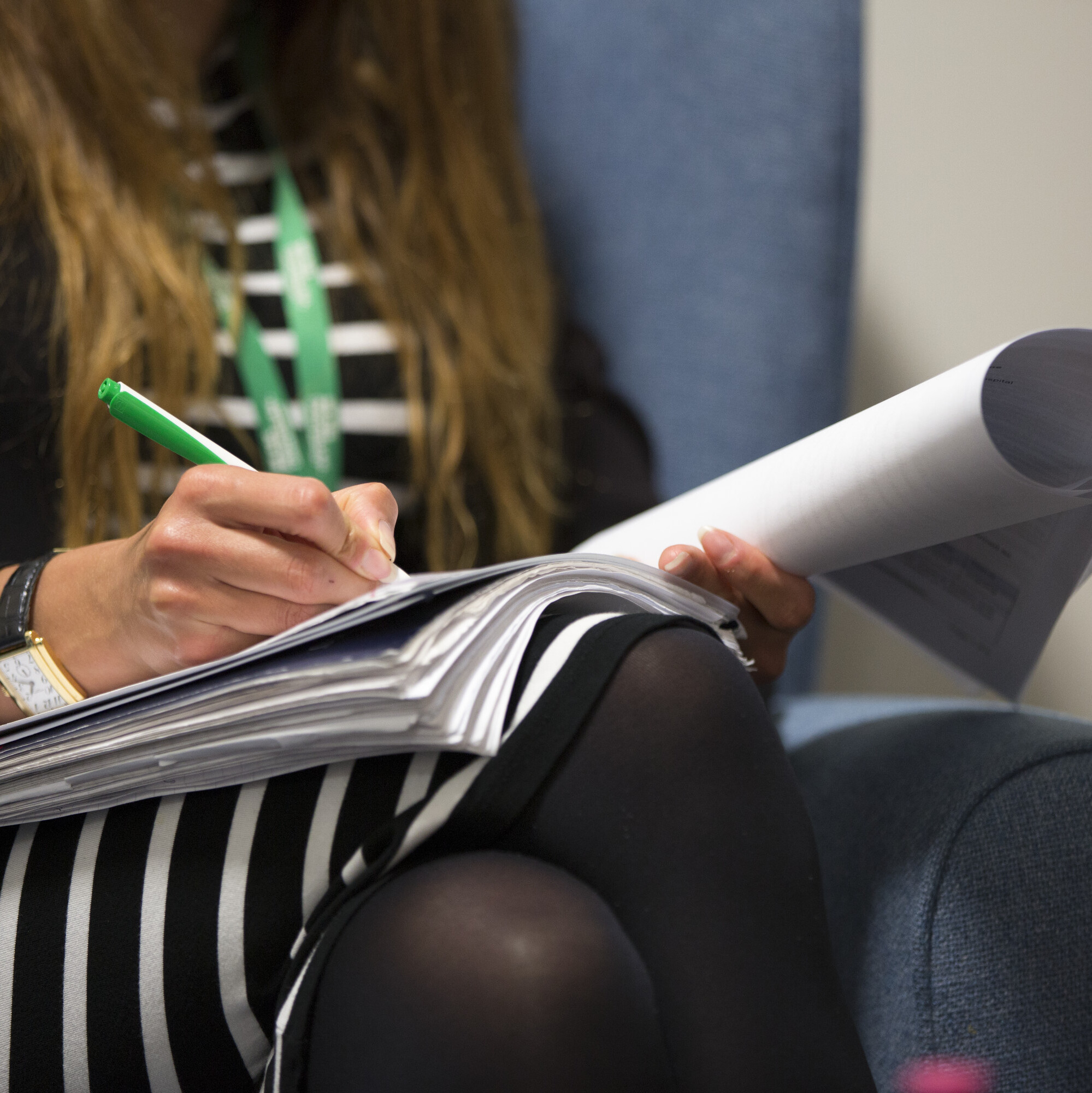 Lady wearing Macmillan lanyard taking notes