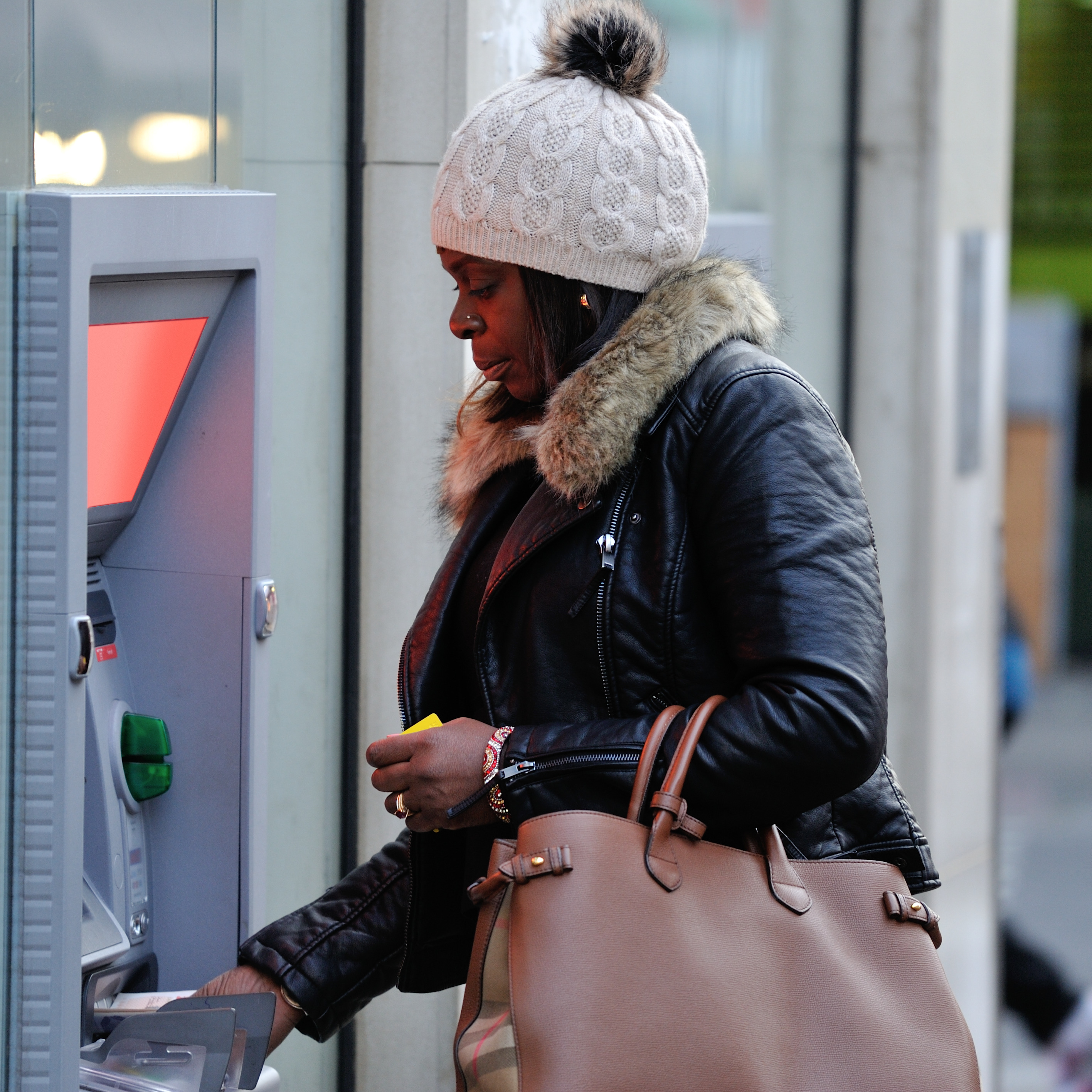 A black woman withdrawing cash (Shola)