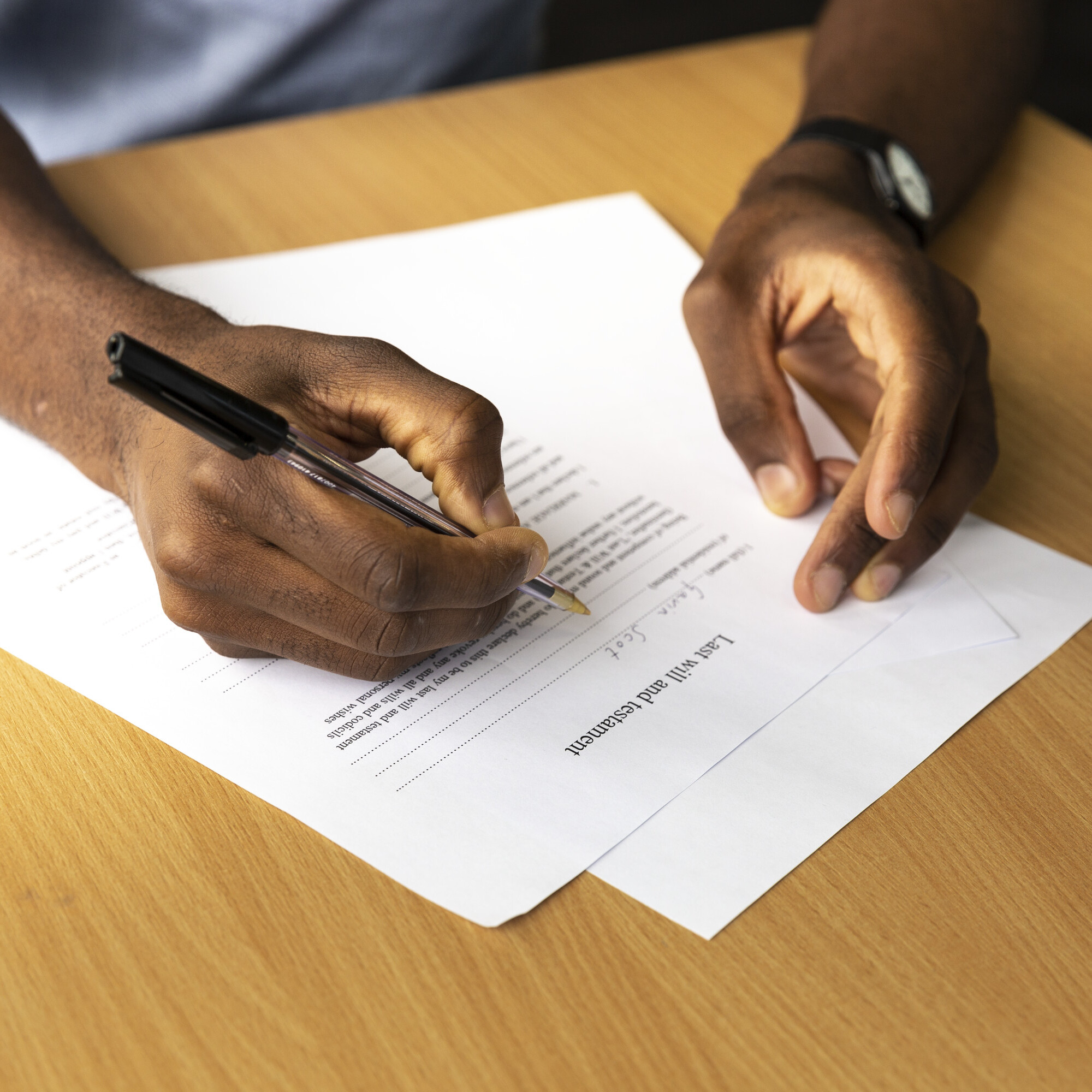 A close-up of man's hands writing a will