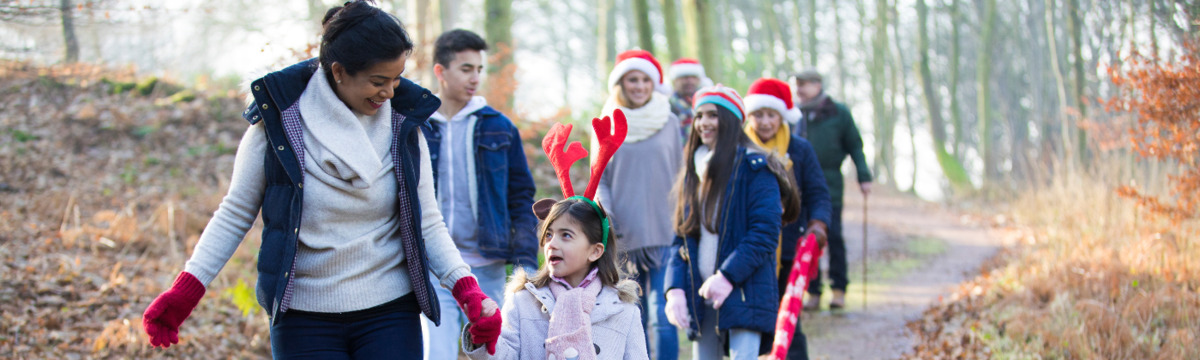 People walking through a path in the woods wearing Christmas hats