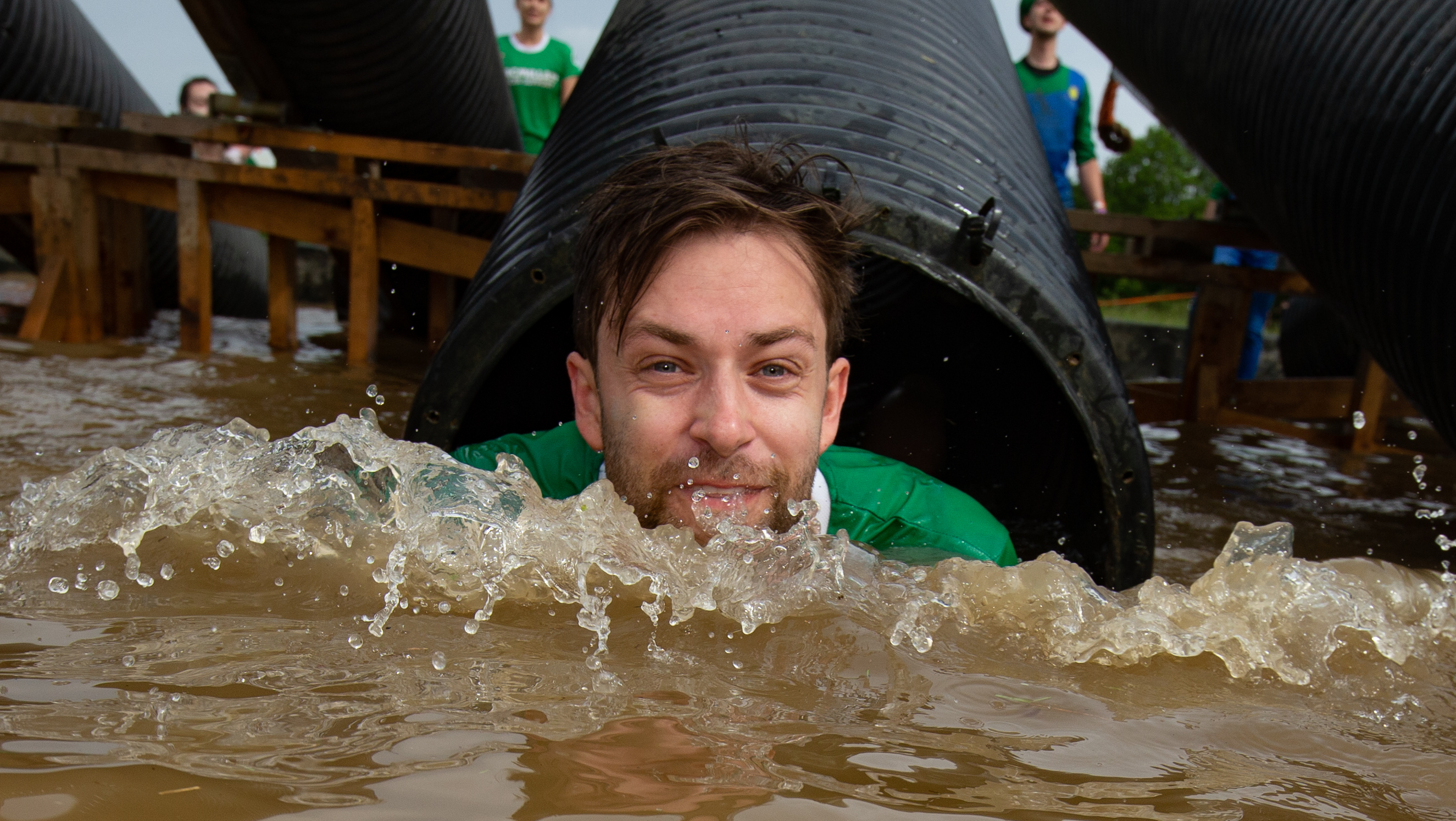 A man in buddy water coming out of a large tube.