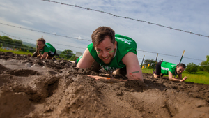 A man army crawling under barbed wire through mud