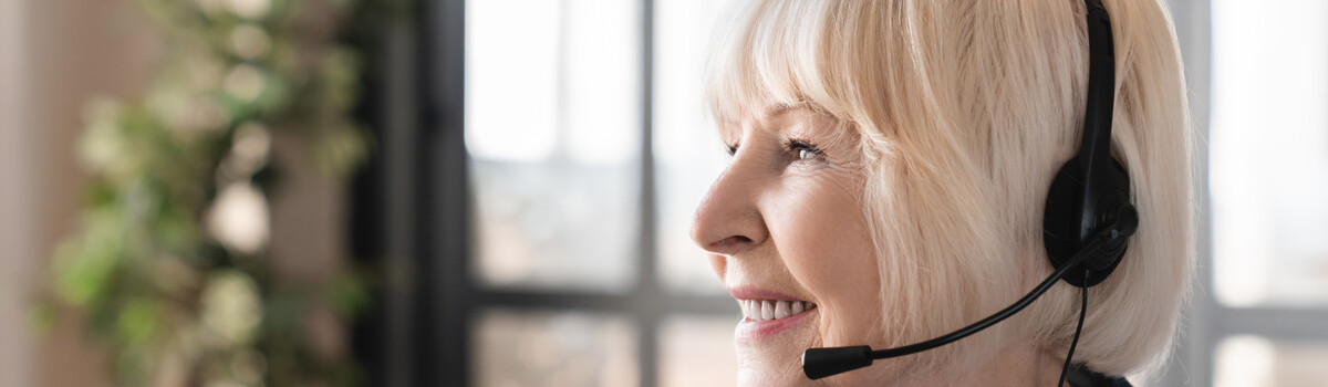 A blonde older woman smiling while on a video call