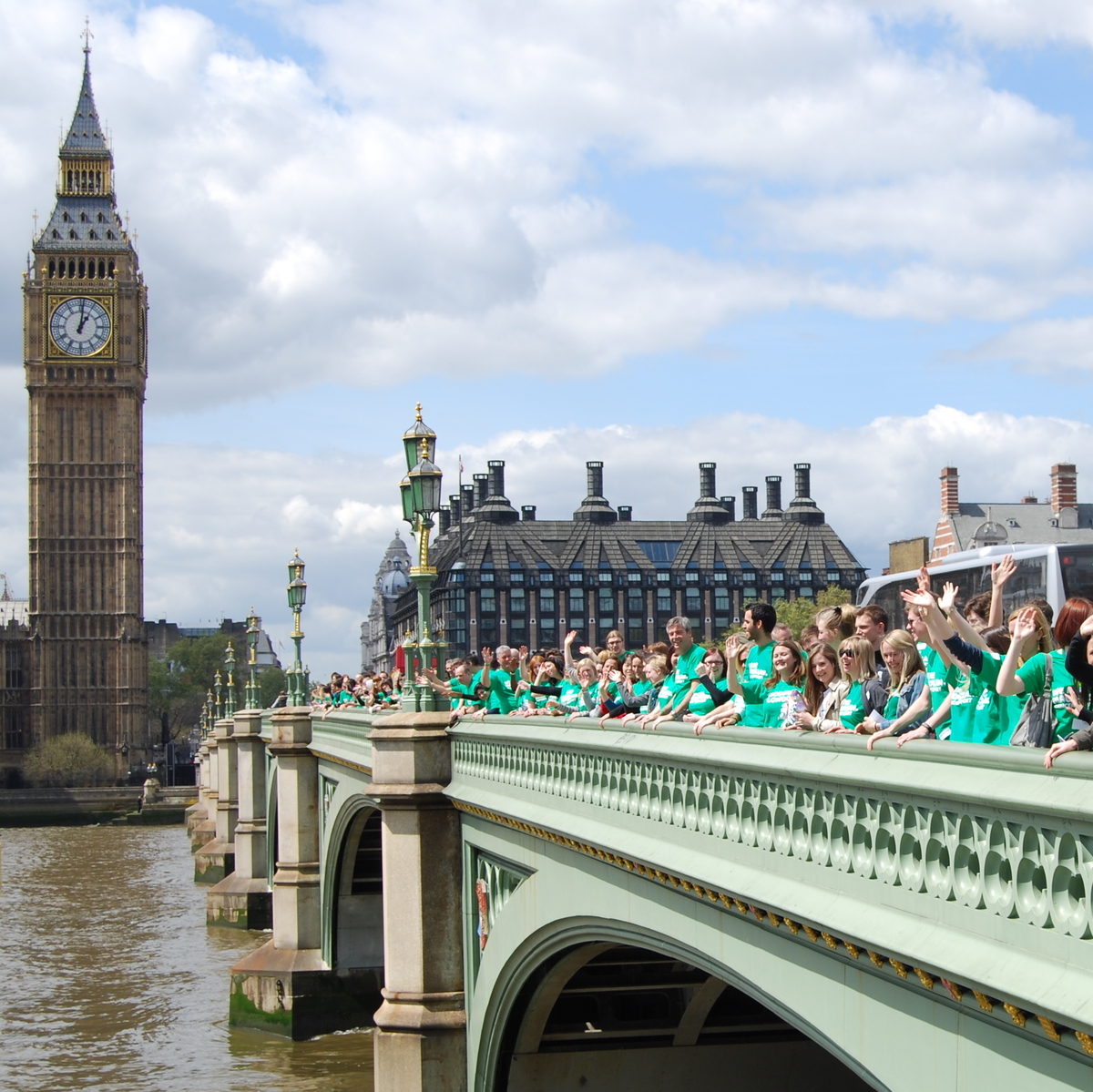 A photograph of a Macmillan staff gathering outside the Houses of Parliament in Westminster. They are wearing green Macmillan t-shirts. 