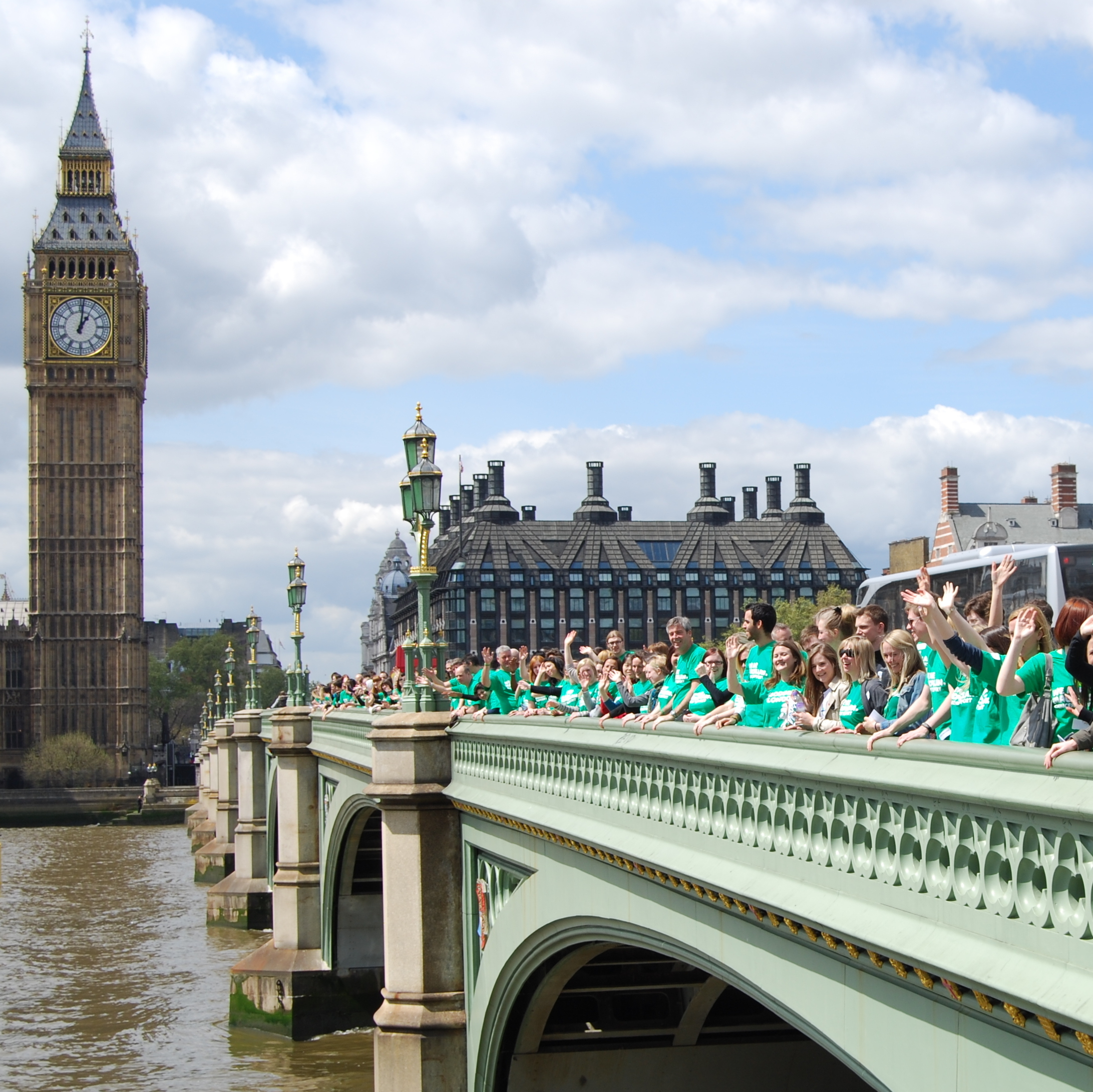 A photograph of a Macmillan staff gathering outside the Houses of Parliament in Westminster. They are wearing green Macmillan t-shirts. 