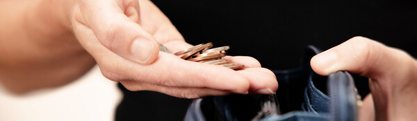 A hand holding a purse and a handful of coins.