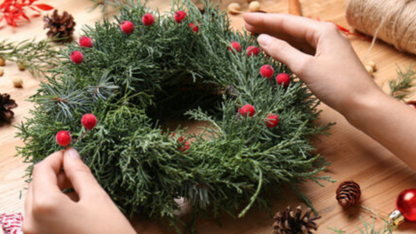 Someone's hands crafting a Christmas wreath