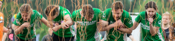 A group of people moving through coloured string and hay,